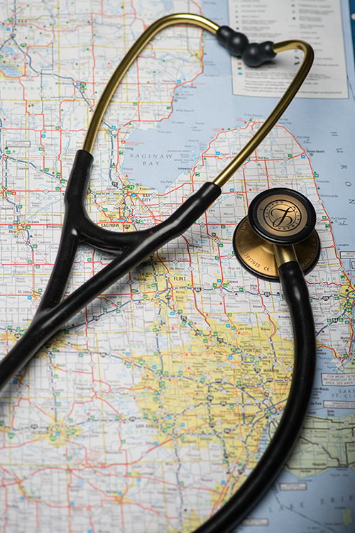A stethoscope placed over a portion of a map of Michigan that includes Detroit and the thumb.